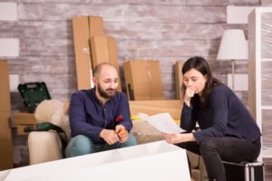 caucasian young couple assembling furniture new apartment girlfriend reading instructions Ally Bohanan Real Estate | Luxury Real Estate in Gastonia, NC